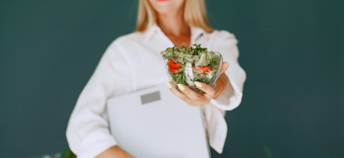 A woman with a vibrant smile offering a fresh salad bowl, promoting healthy eating.
