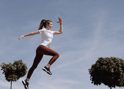 Athletic woman in action jump against a blue sky background. Captures fitness in motion.